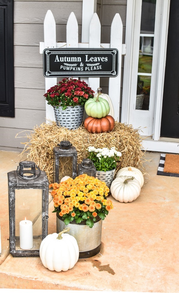Farmhouse fall front porch with lots of mums, hay and pumpkins-35